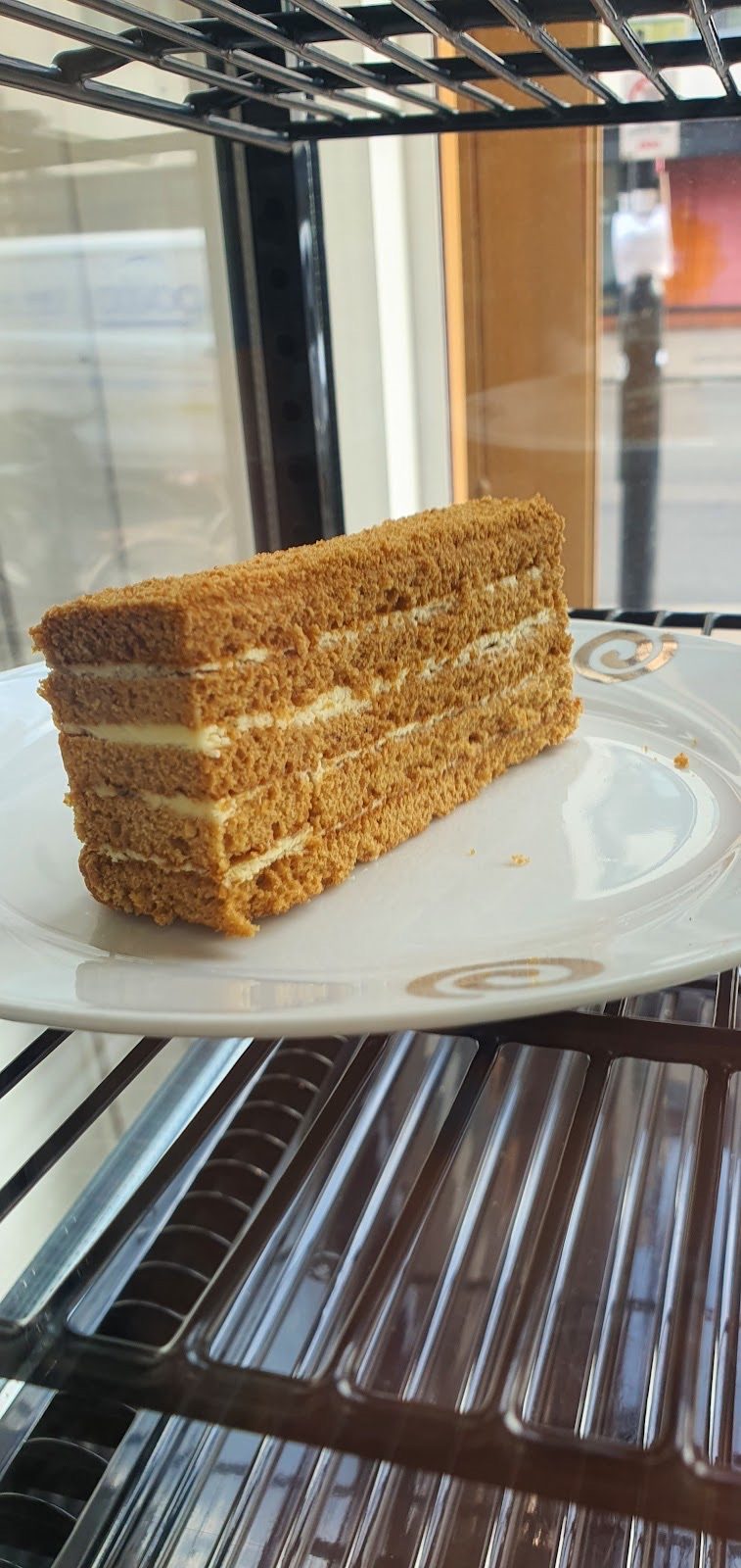 A tall slice of honey layer cake in the display fridge